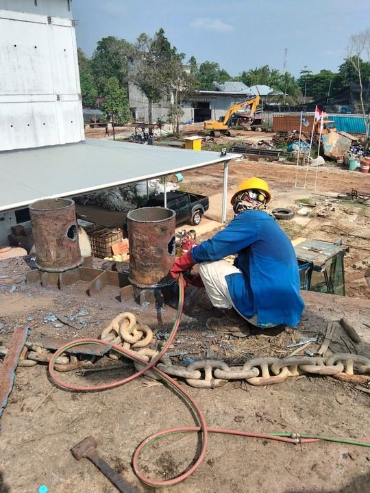 Pemotongan baja oleh pekerja dengan APD lengkap